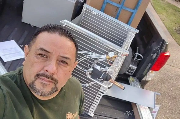 Technician with a new AC unit ready for installation in Dallas, TX.