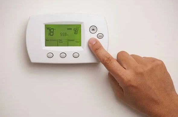 Hand adjusting a new smart thermostat after professional installation in Austin, TX.